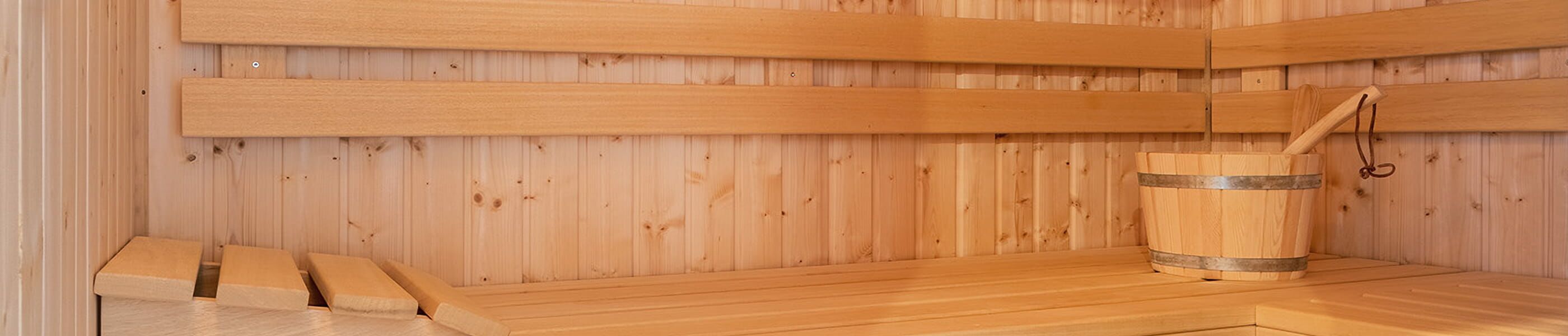 Sauna aus Holz mit Sitzflächen und Aufgusseimer
