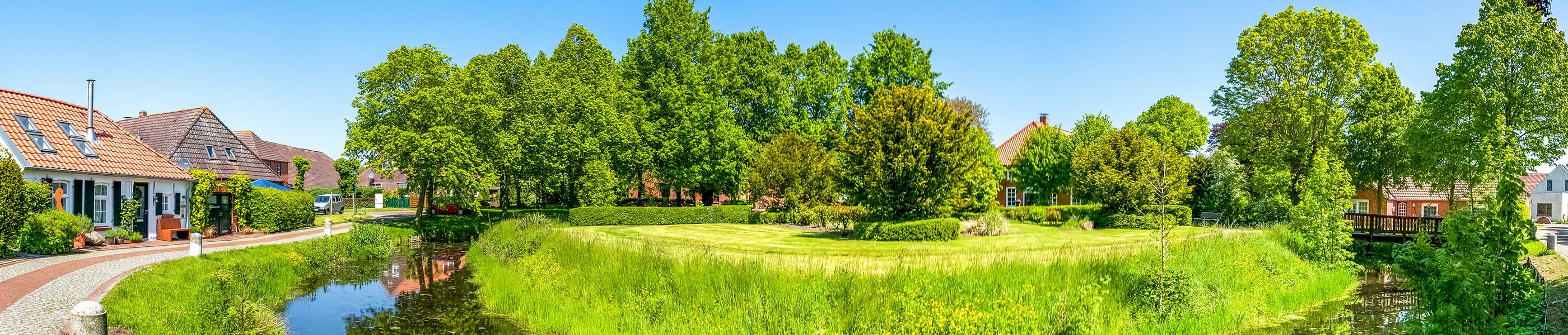 Dorfansicht mit Teich, Wiesen und Häusern im Grünen