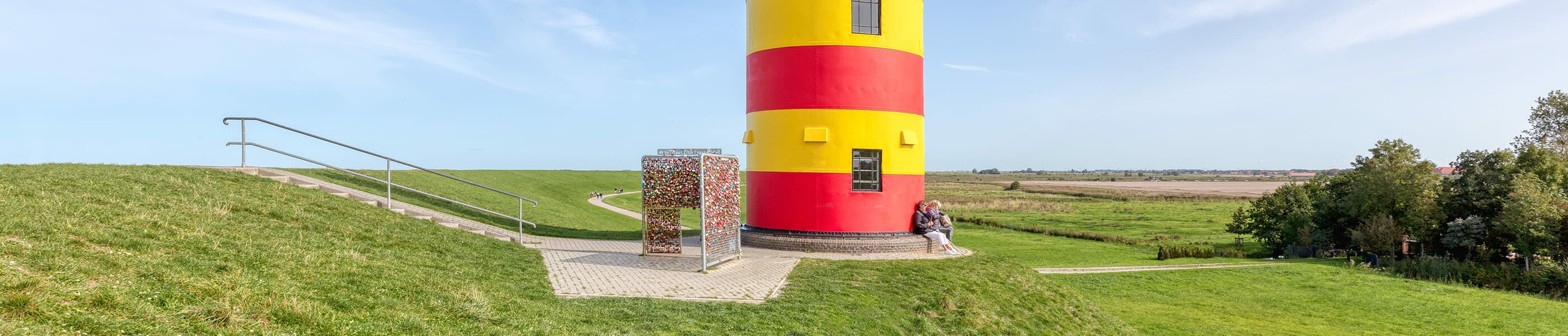 Pilsumer Leuchtturm am Deich mit Blick über weite Marschlandschaft