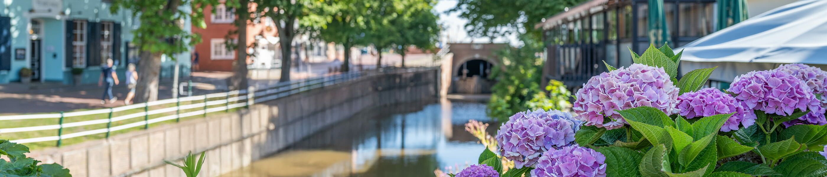 Kanal in Greetsiel mit Brücke und Hortensien im Vordergrund