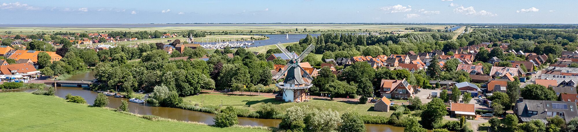Luftaufnahme von Greetsiel mit grünen Wiesen und Nordsee im Hintergrund