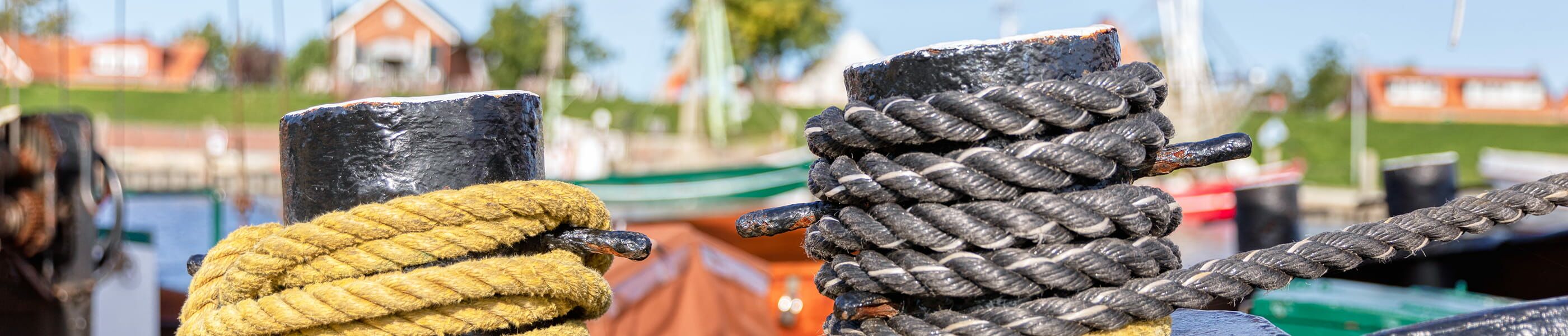 Taue um Poller im Hafen von Greetsiel mit Booten im Hintergrund