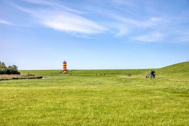 Familienurlaub in Greetsiel – Weite Wiesen und Leuchtturm Pilsum im Hintergrund
